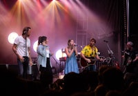 a group of people singing on stage at a concert